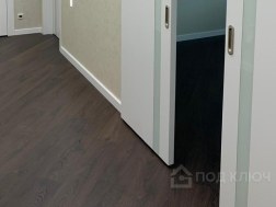 Ремонт квартиры под ключ: коридор с тёмным ламинатом и белыми дверями со стеклянными вставками